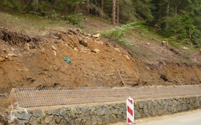 Wysokie oddzielenie drogi i ścieżki rowerowej stromym zboczem w Prášilech na Szumawie