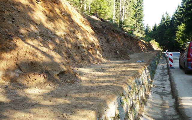 Wysokie oddzielenie drogi i ścieżki rowerowej stromym zboczem w Prášilech na Szumawie