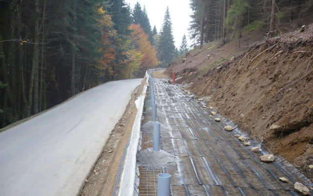 Wysokie oddzielenie drogi i ścieżki rowerowej stromym zboczem w Prášilech na Szumawie