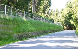 Wysokie oddzielenie drogi i ścieżki rowerowej stromym zboczem w Prášilech na Szumawie